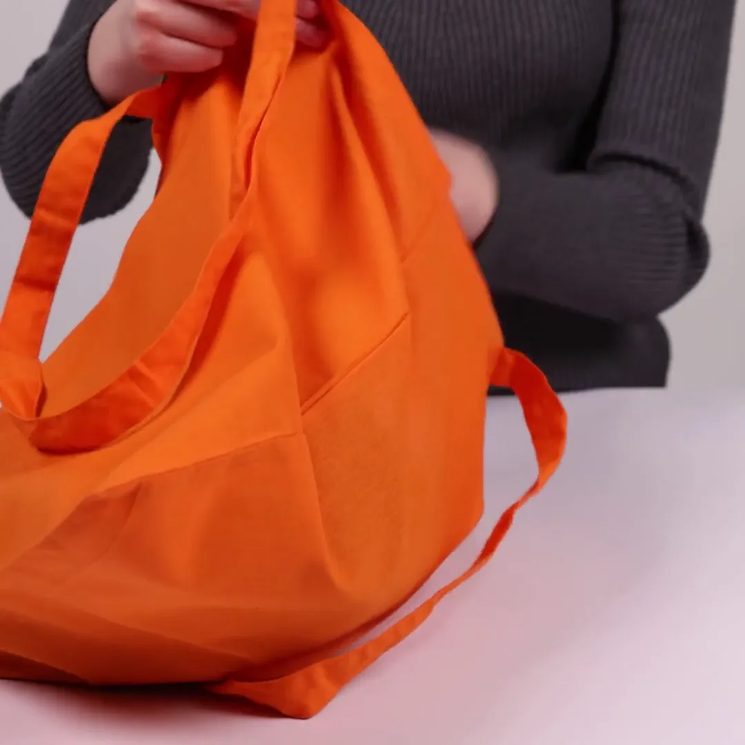 Bomullsnett, 140 g/m², vist av en person i produktvideoen – oransje