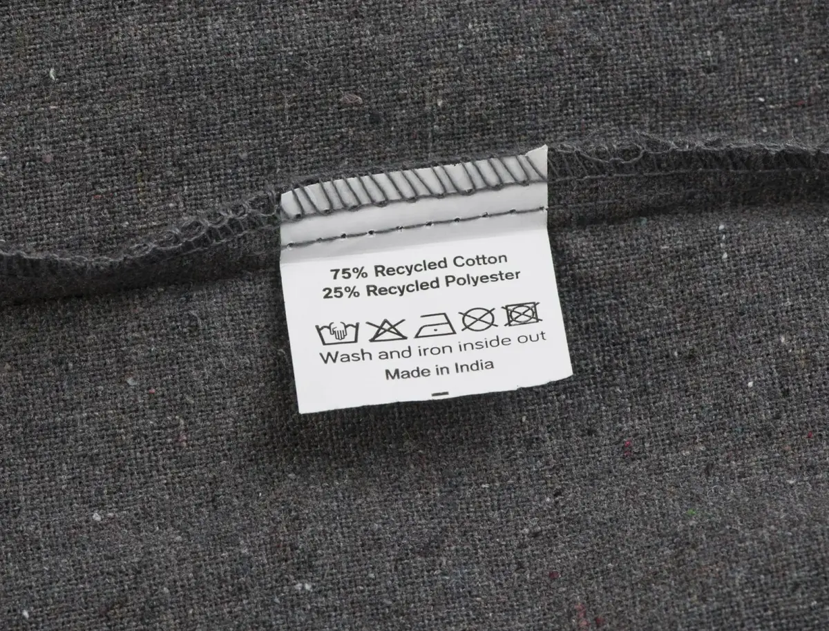 Handlenett – etikett med 75 % resirkulert bomull, 25 % resirkulert polyester og vaskesymboler.